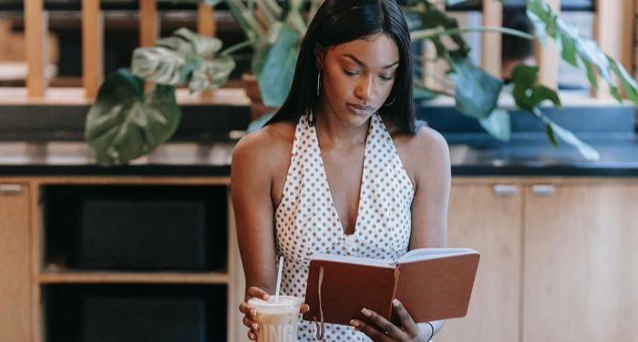 brown skinned Black woman reading a book in a cafe.jpg.optimal