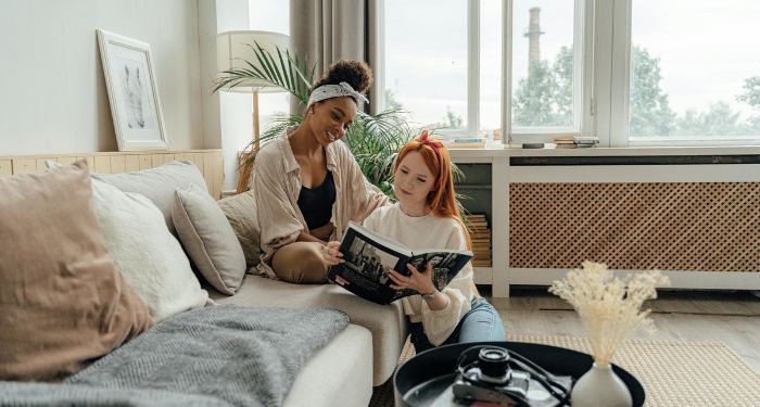 a brown skinned Black woman and a fair skinned white woman sitting and reading a book together.jpg.optimal