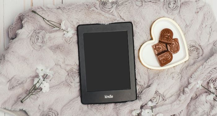 kindle on gray blanket with heart shaped plate of chocolates nearby feature.jpg.optimal