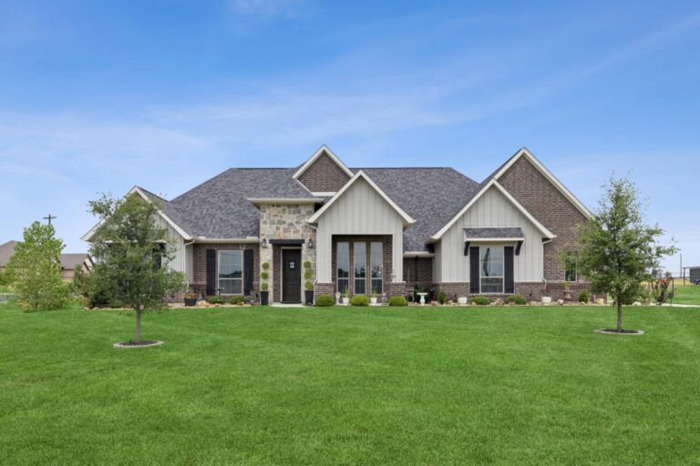 mixed stone and brick single family home with large manicured lawn and trees