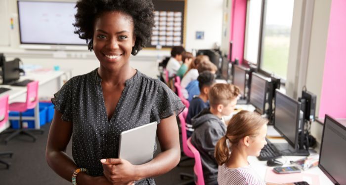 Image of a Black woman in front of a room of kids on computers.jpg.optimal